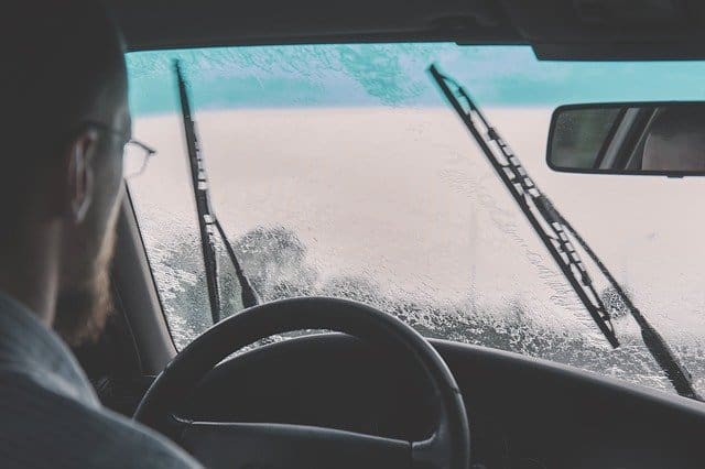 Driver seen through a rain-covered windshield