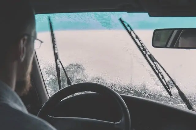 Driver seen through a rain-covered windshield